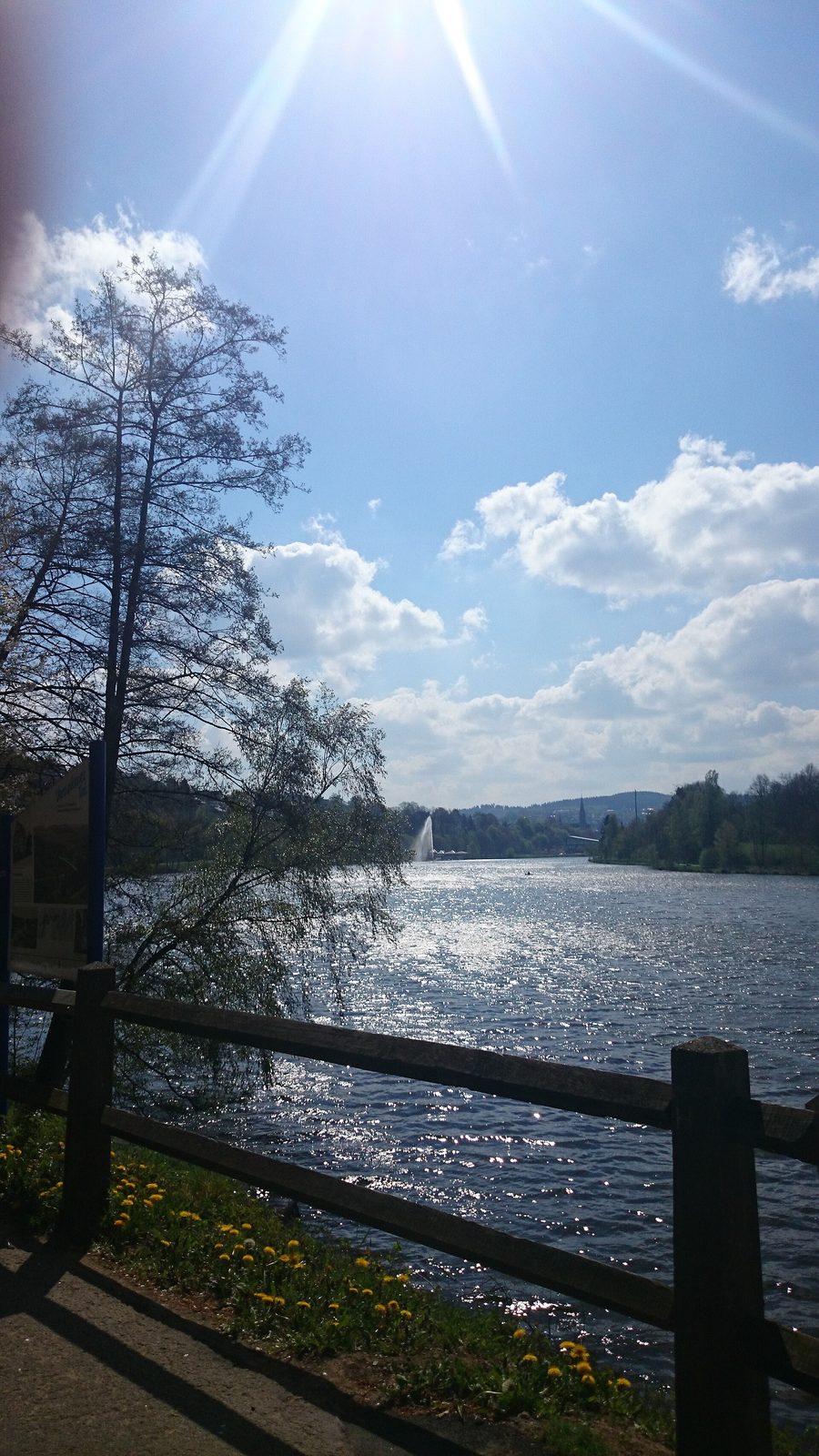 Sonniger Blick auf den Biggesee bei Olpe mit Wasserspiel, Bootshaus und Olper Schwimmbad im Hintergrund